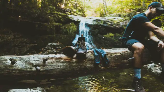 man resting with socks and shoes resting on tree.