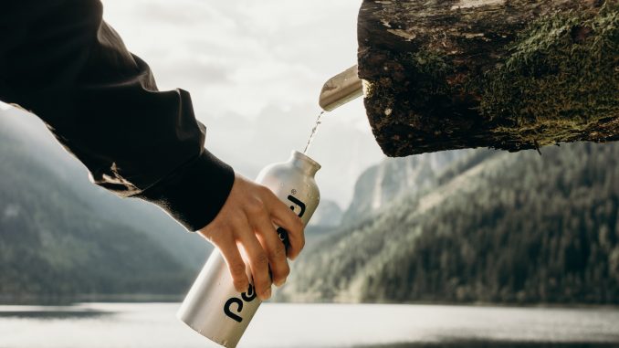 person holding gray sports bottle near nozzle