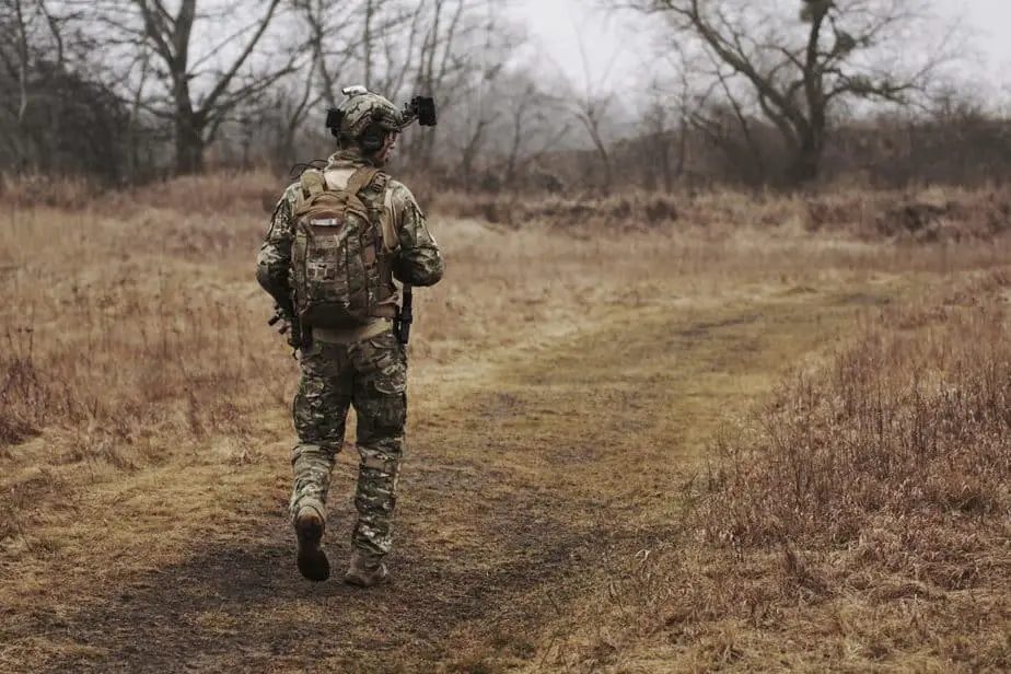 Soldier walking on brown grass field