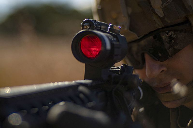 Soldier using weapon with aiming system attached to the top of the weapon.