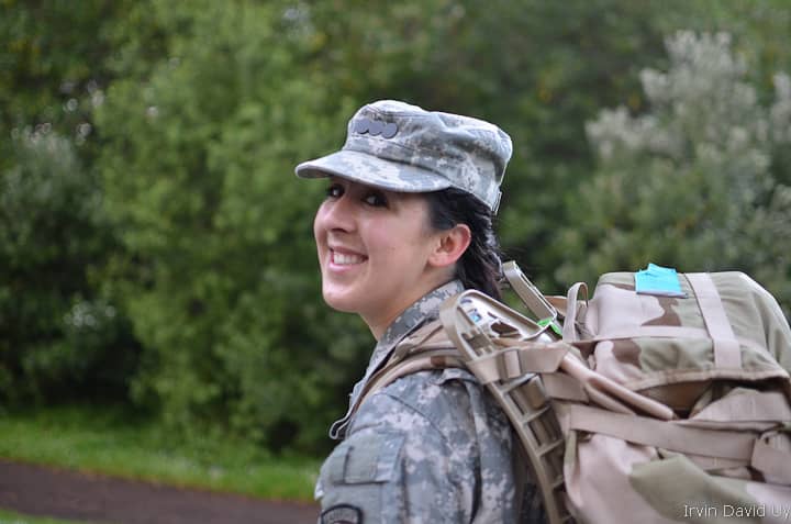 A women in the military rucking while wearing a rucking with an external frame.