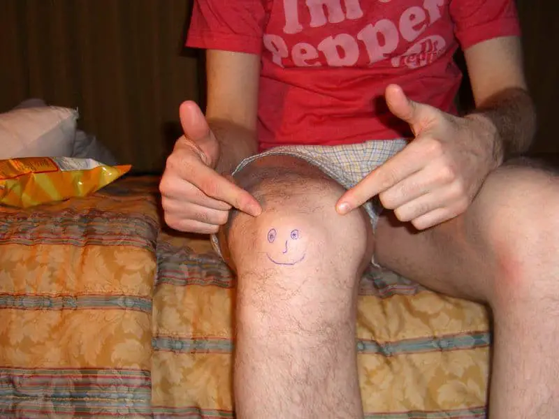 Man sitting down with a smile drawn on his knee.
